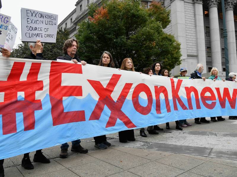 a protest with a sign that says 'Exxon knew'