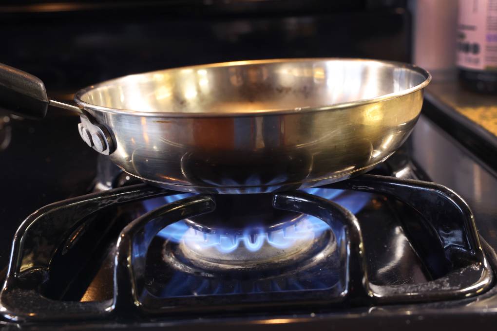 a pan sits on flames burning on a natural gas-burning stove.