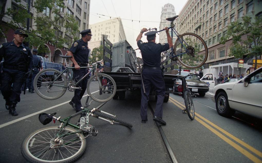 Police officers throw bicycles into the back of a truck in downtown San Francisco.