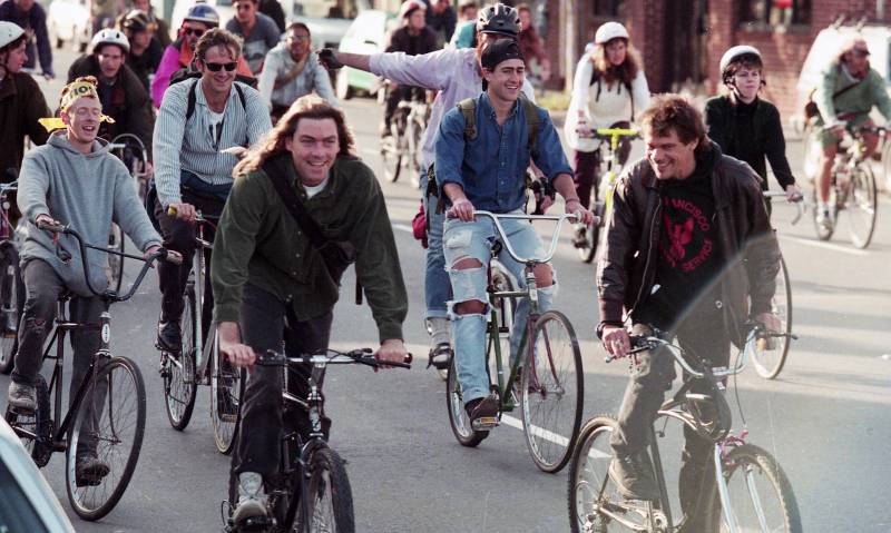 A group of cyclists happily riding through San Francisco streets together. 