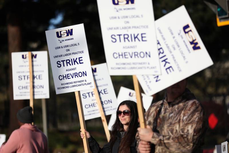 Strikers hold placards that feature words "strike" and "Chevron"
