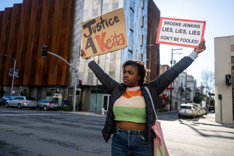 Kaylah Williams May holds signs while listening to a speaker during a rally for Keita O'Neil outside the Hall of Justice at 850 Bryant Street in San Francisco on March 1, 2023.