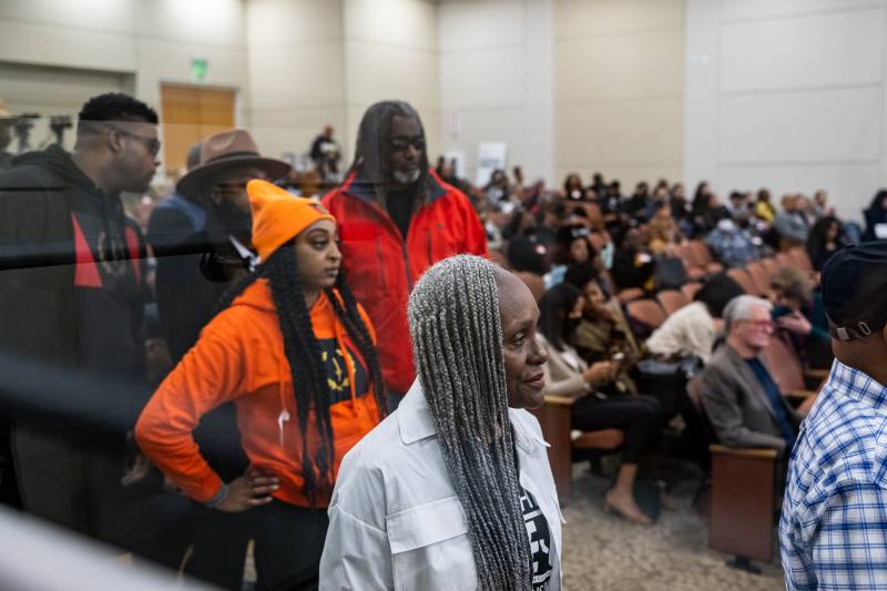 African Americans in a conference hall look toward the podium.