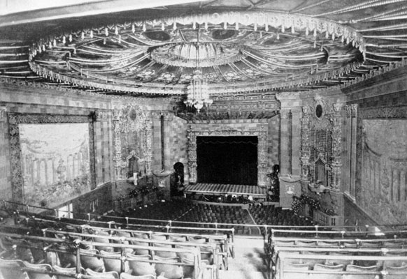 Black and white image taken from the balcony of a classic, highly decorated movie theater.