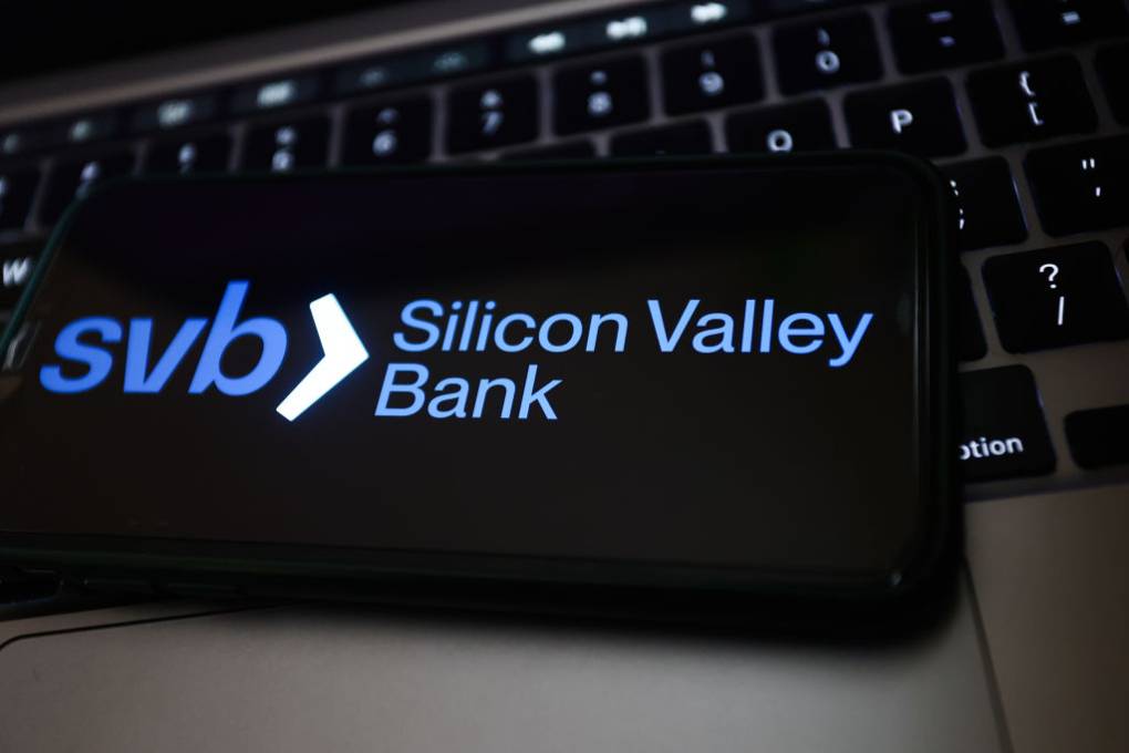 A logo displayed on a phone screen and a laptop keyboard that says "SVB Silicon Valley Bank."