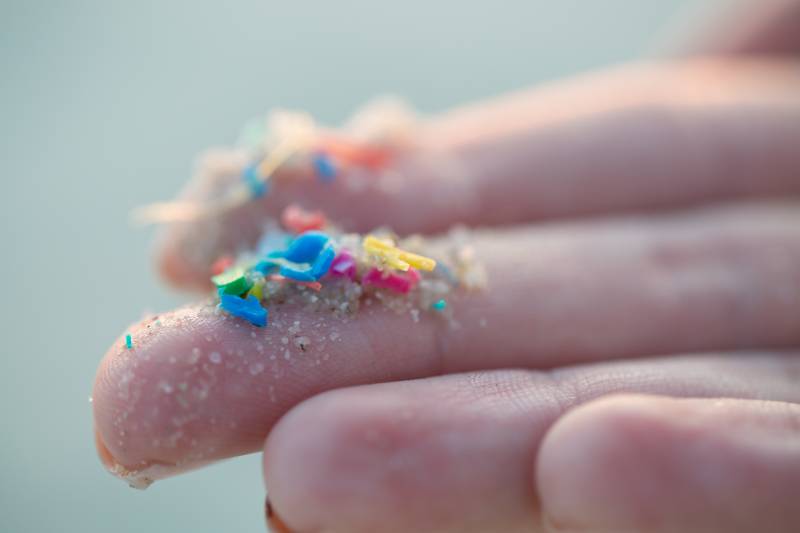 Someone's hand showing multicolored microplastics.