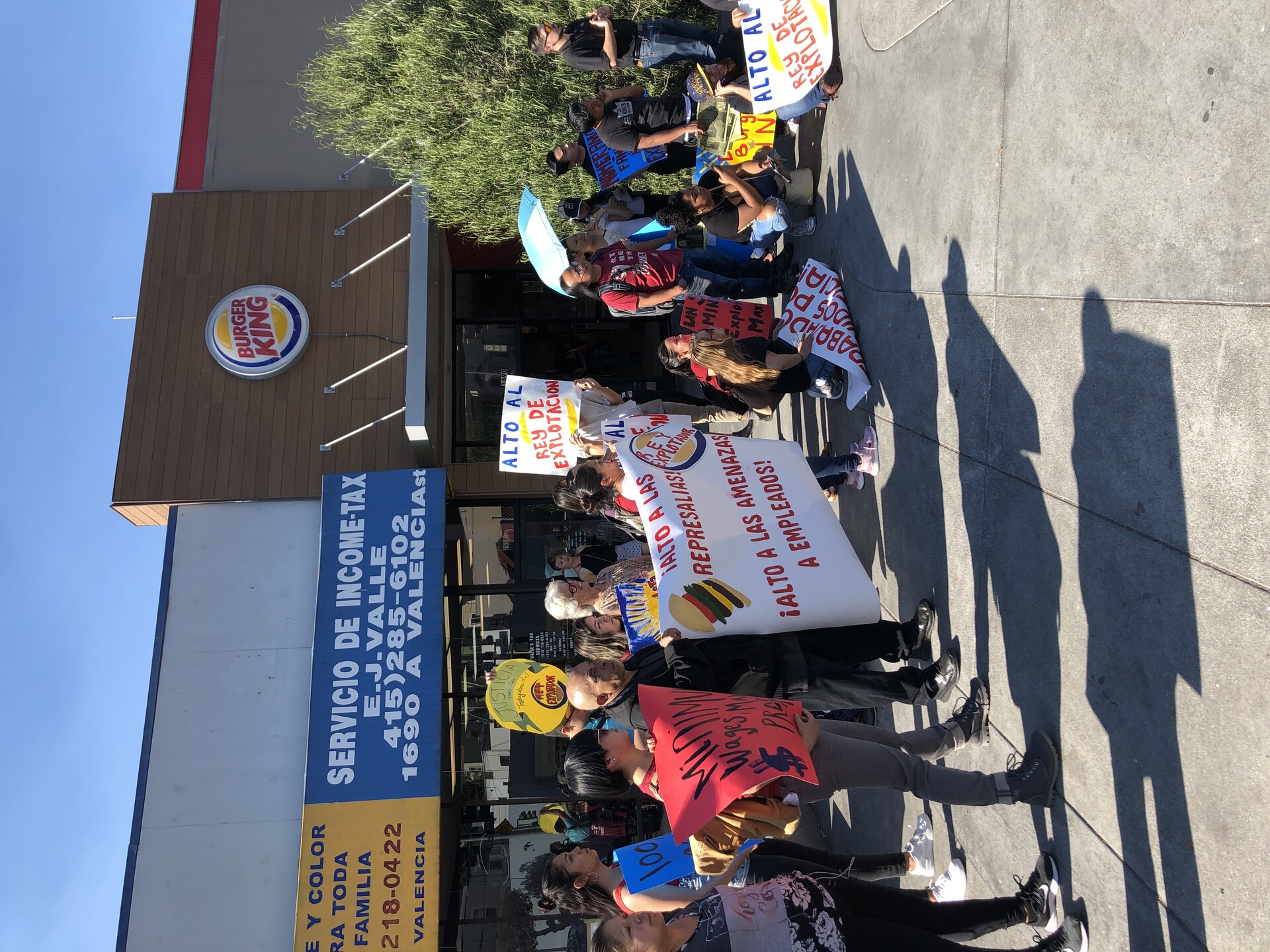 Dozens of men and women holding signs in front of a Burger King franchise in Oakland, California.