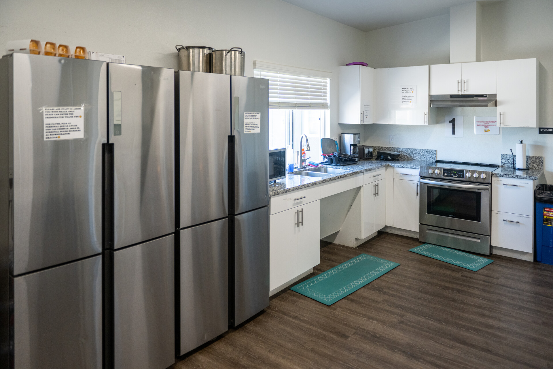 A new-looking kitchen with 2 stainless steel fridges, a sink and an oven.