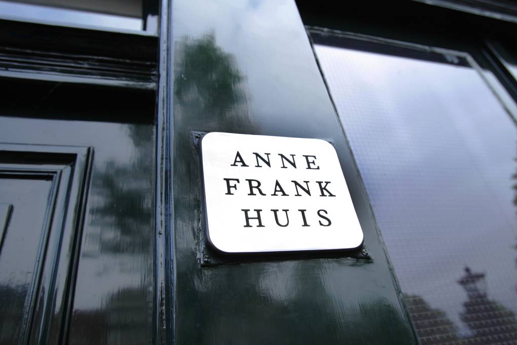 A closeup photo of a sign reading 'Anne Frank Huis' on the side of a building
