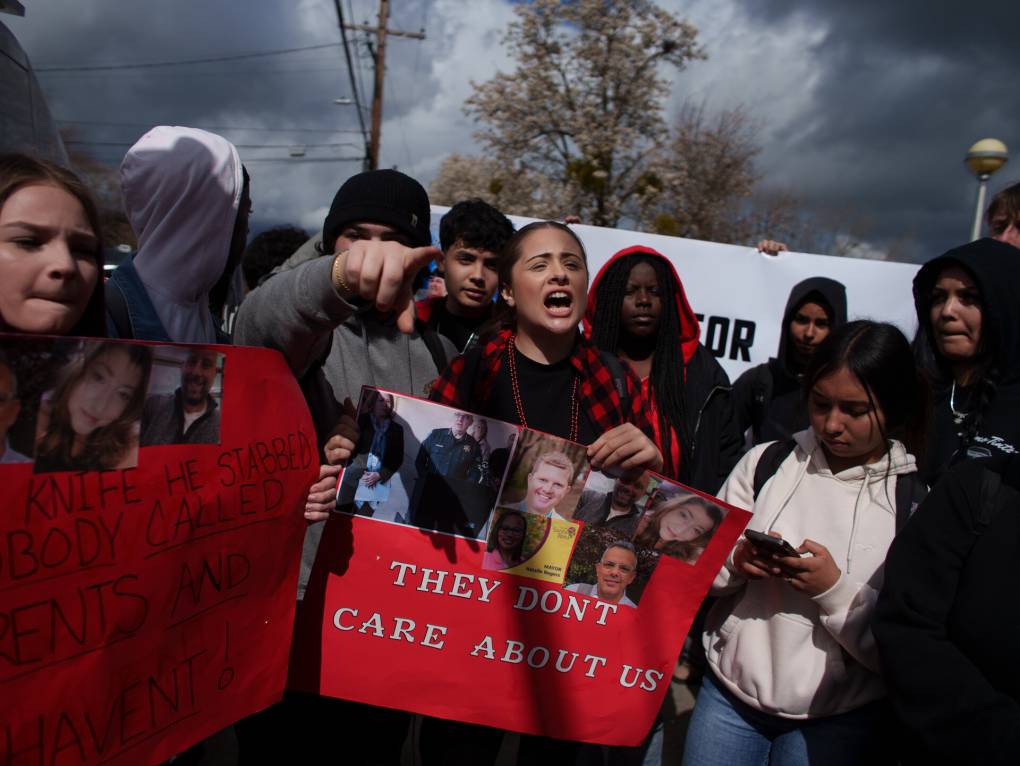 a group of young people holding red signs with images stand outside.