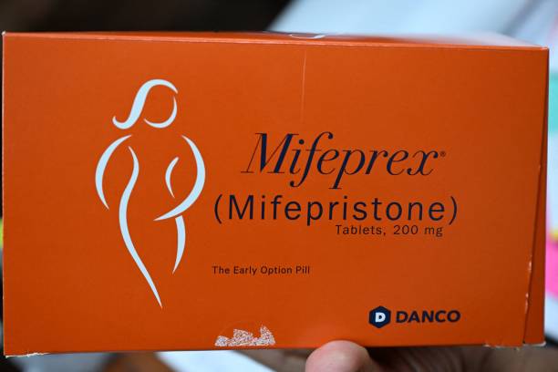 An orange rectangular box of pills with an outline of a female figure and the words "Mifeprex (mifepristone)" on the box.