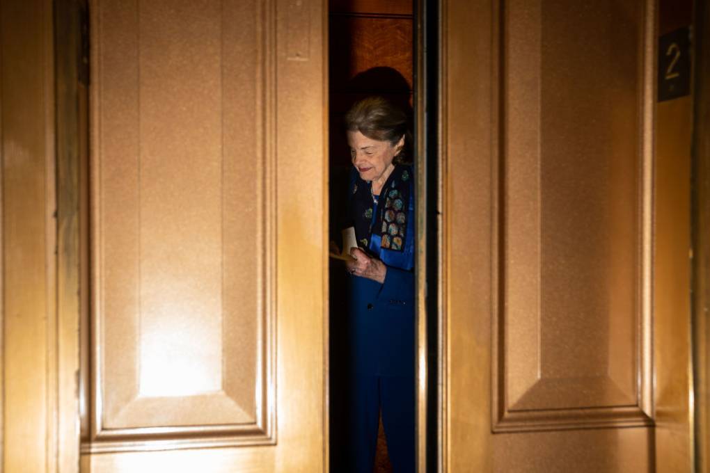 Sen. Dianne Feinstein is seen behind a slightly open large wooden door.