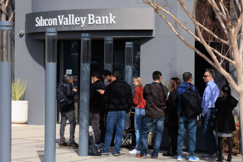A line of people outside a grey building with Silicon Valley Bank written above the entrance.