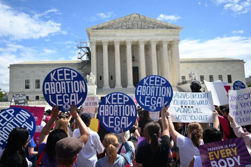 Protesters outside a neoclassical white building with columns holding signs that read "Keep Abortion Legal."
