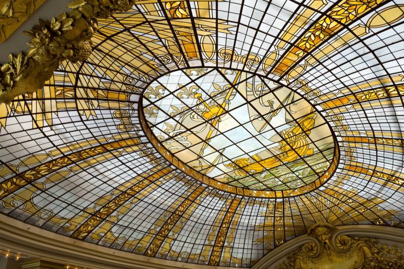 A large stained glass ceiling in ambers and gold depicting a sailing ship
