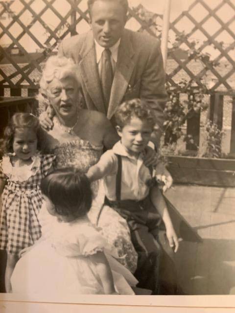 A vintage black-and-white photo of a man and woman who is kneeling down holding three children.