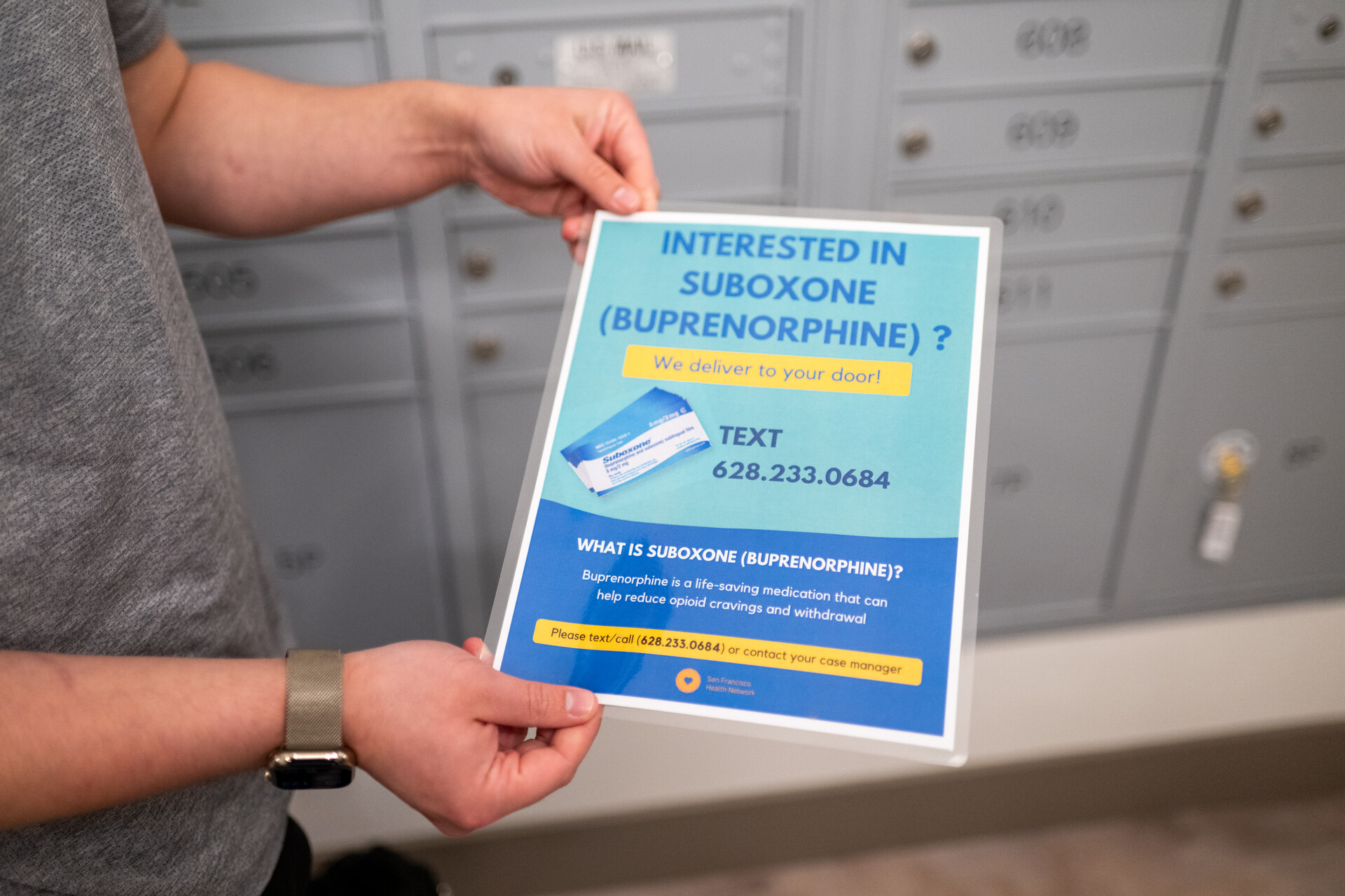 A man's hands hold a laminated flyer that reads, "Interested in Suboxone (Buprenorphine)? Text 628.233.0684."