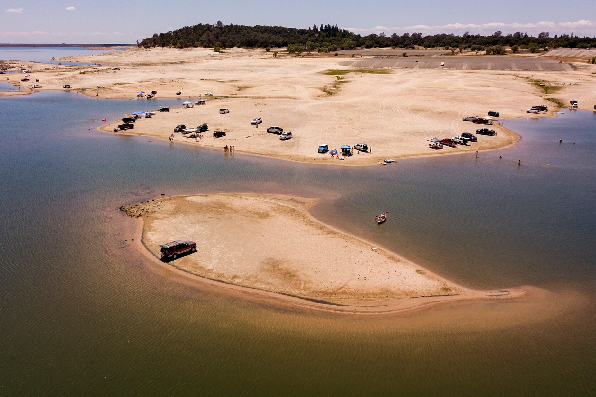 An aerial view of Folsom Lake with very little water. Vehicles are parked on patches of land where water should be.