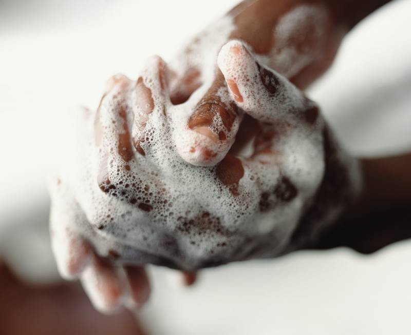 A photo of a person's darker-toned hands covered in soap foam