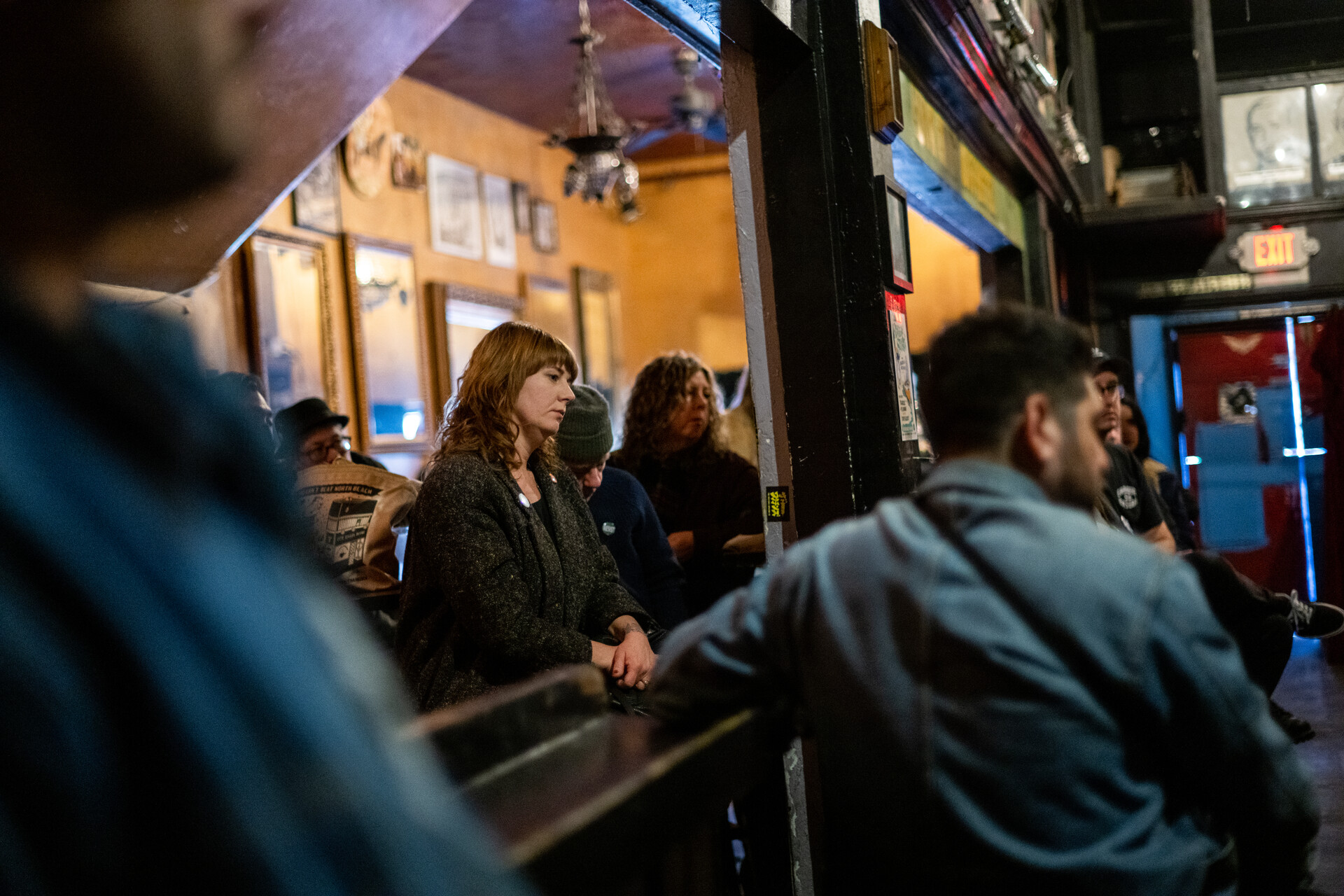 People stand and listen at a bar