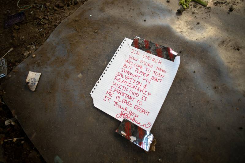 A written note in red ink on lined notebook paper lays on the ground.
