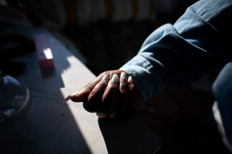 Manicured and stylized long fingernails in a photo of an African American woman's right hand with a denim jacket sleeve.