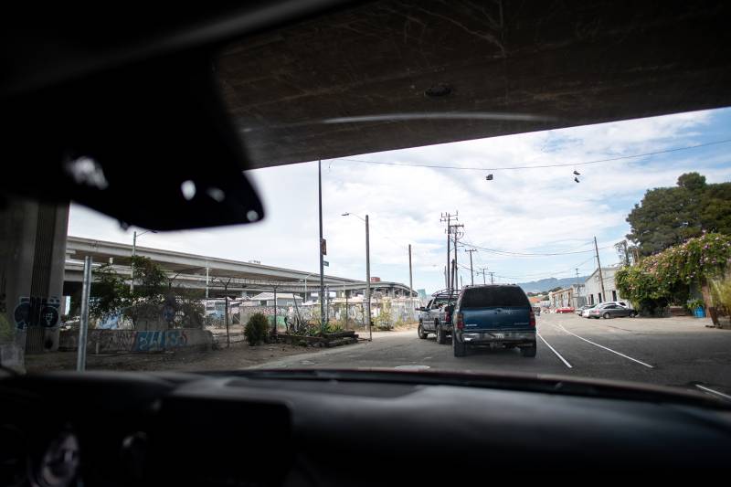 A car being towed ahead seen from inside another car driving behind it as they pass under an overpass.