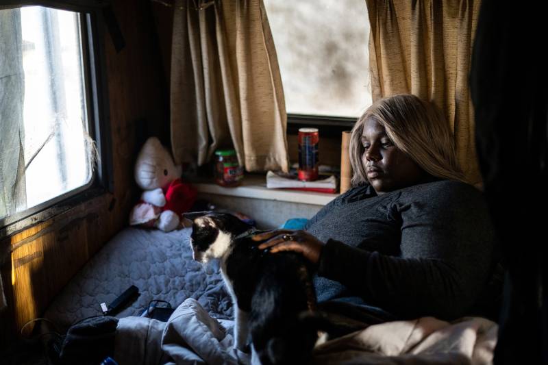 An African American woman lying in bed with her cat