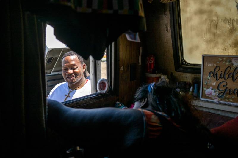An African American man smiles as he looks through an RV window.