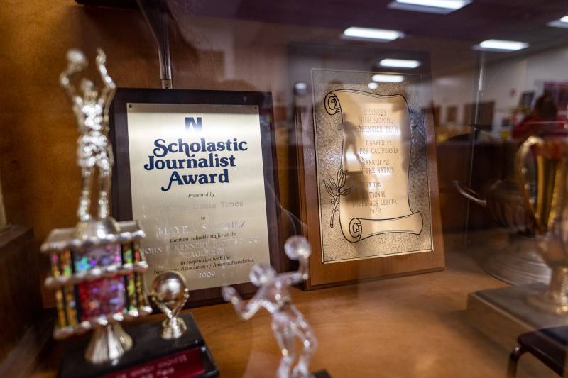 A display of awards and trophies. One award in particular reads "Scholastic Journalist Award."