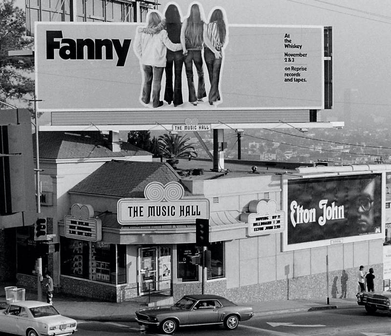 A vintage black and white image of a billboard above a building of four women with their backs turned with a message that says "Fanny."