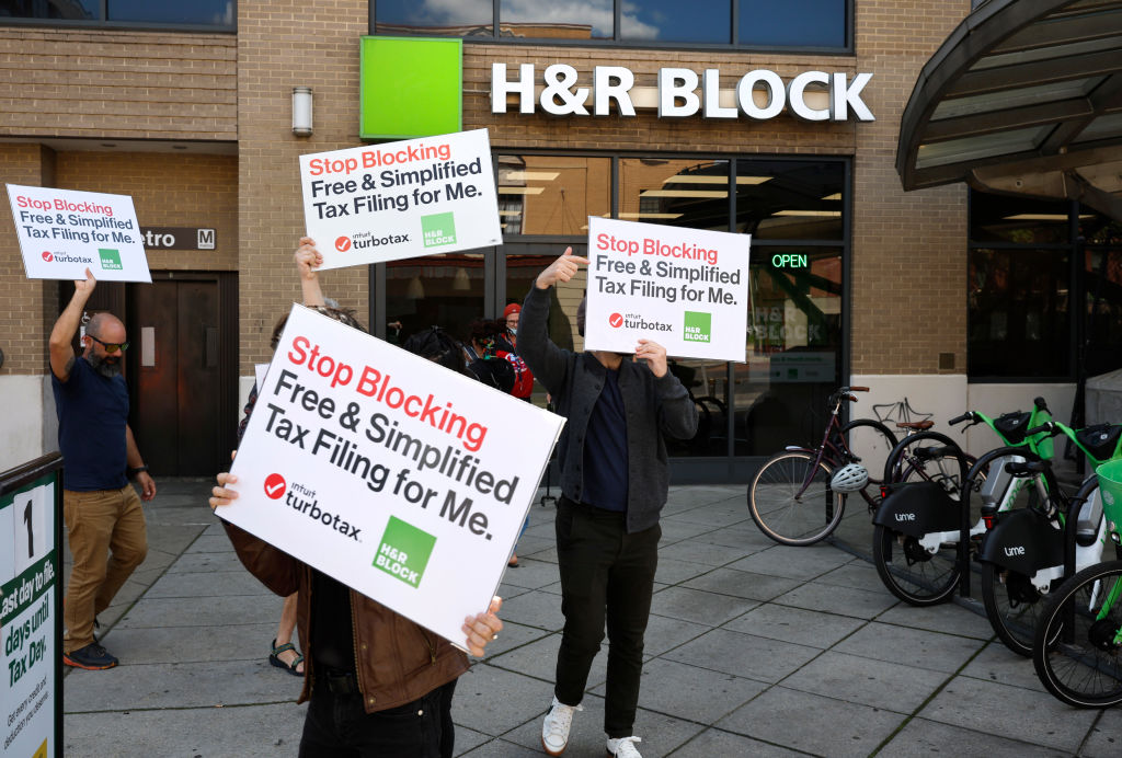 People outside an H&R Block office protest with signs.