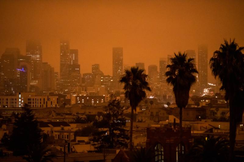 A photo of a polluted orange-colored city skyline with palm trees.