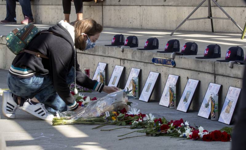 A woman lays flowers in front of framed photographs.