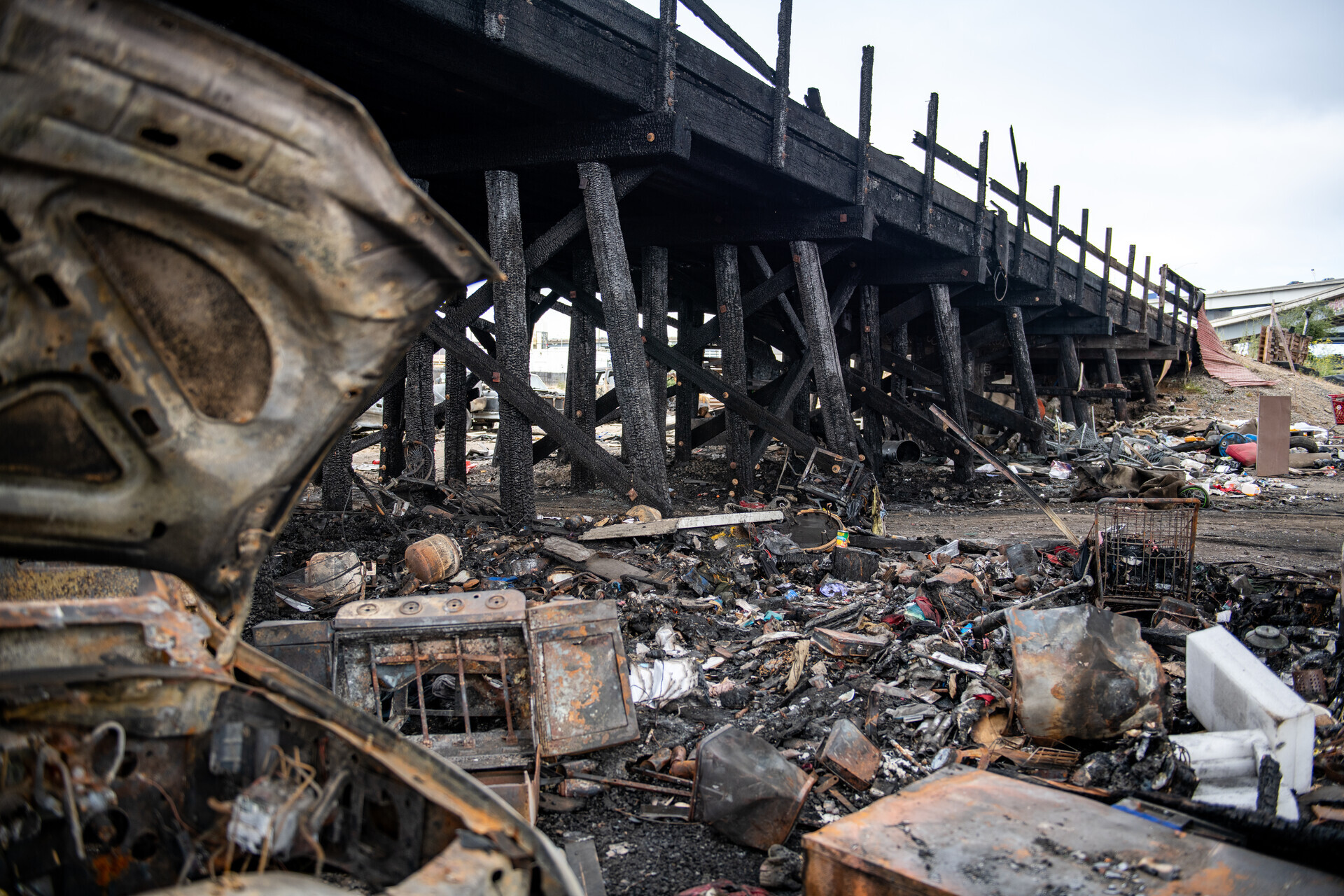 Charred cars, metal, belongings and debris are scattered throughout an open field.