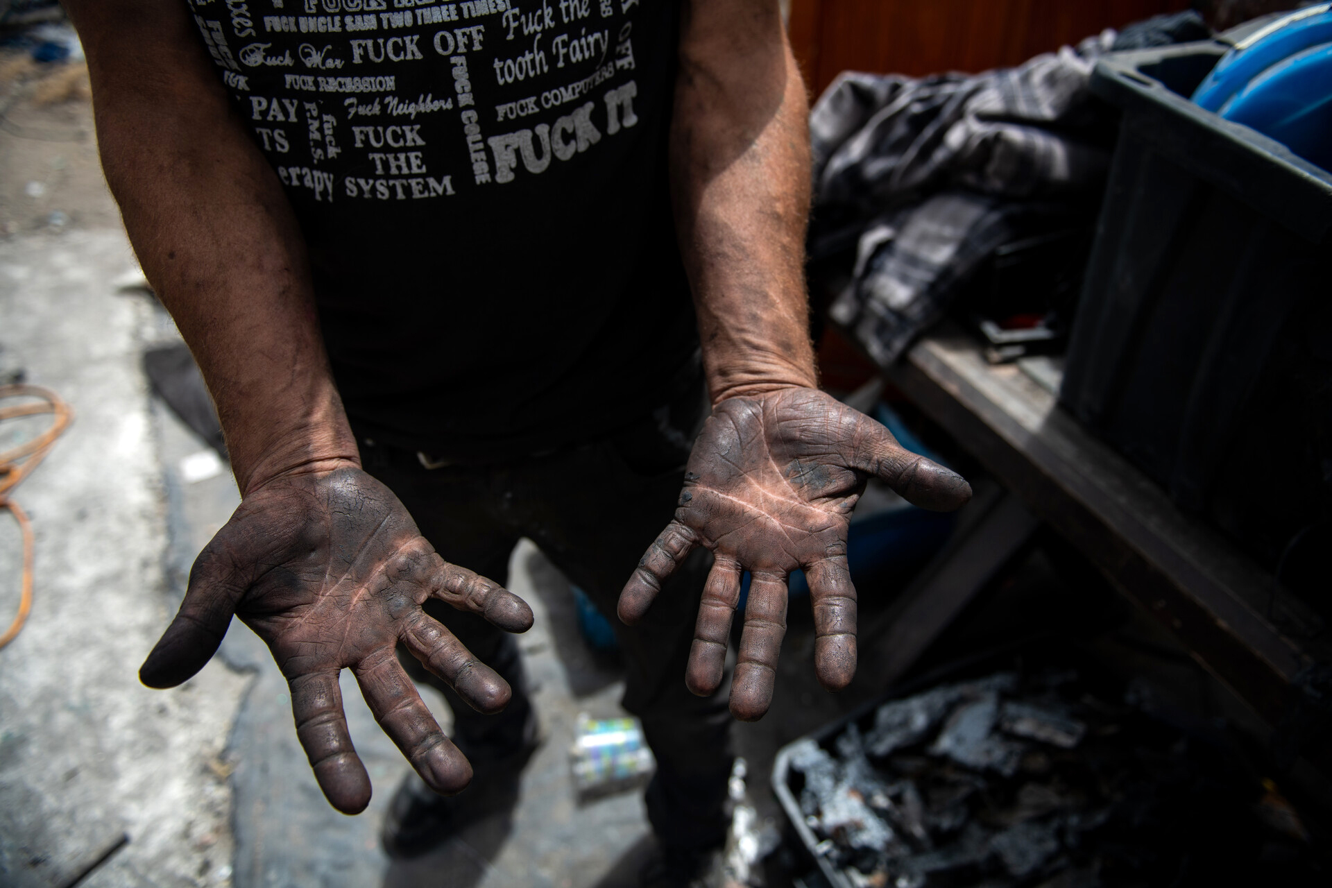 A closeup shot of a man's hands covered in black soot from a previous fire.