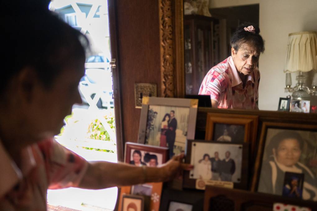 An older African American woman looks at photos of her son and family.