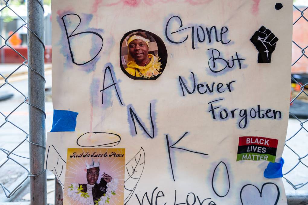 white handmade poster with a circular pasted-on photo of a smiling Black man that reads 'BANKO'