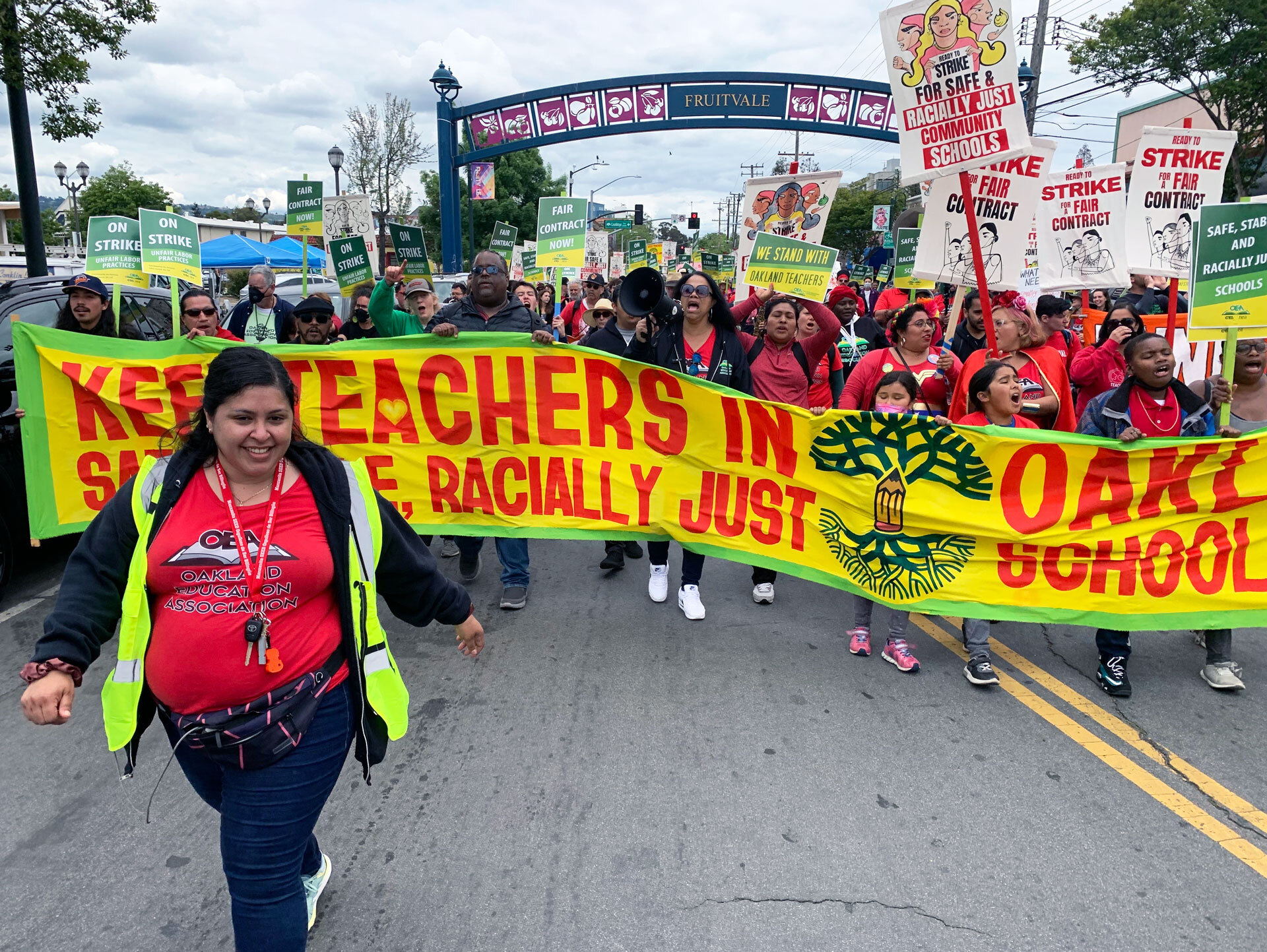 Striking teachers marching holding a big colorful banner.
