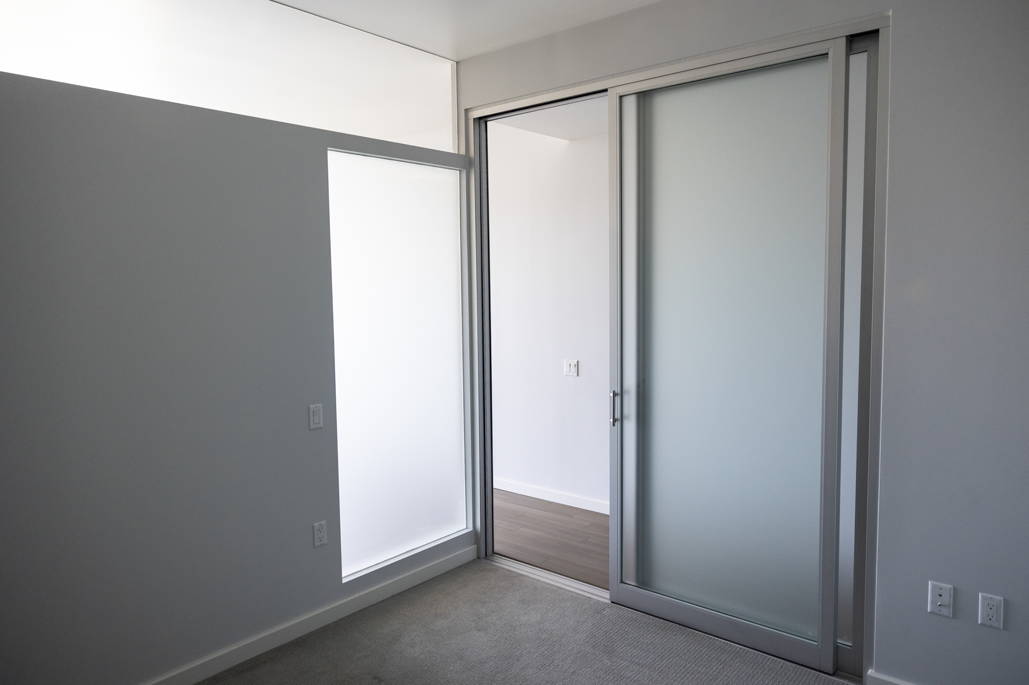 A large empty room with a glass sliding door and glass panels in one wall.