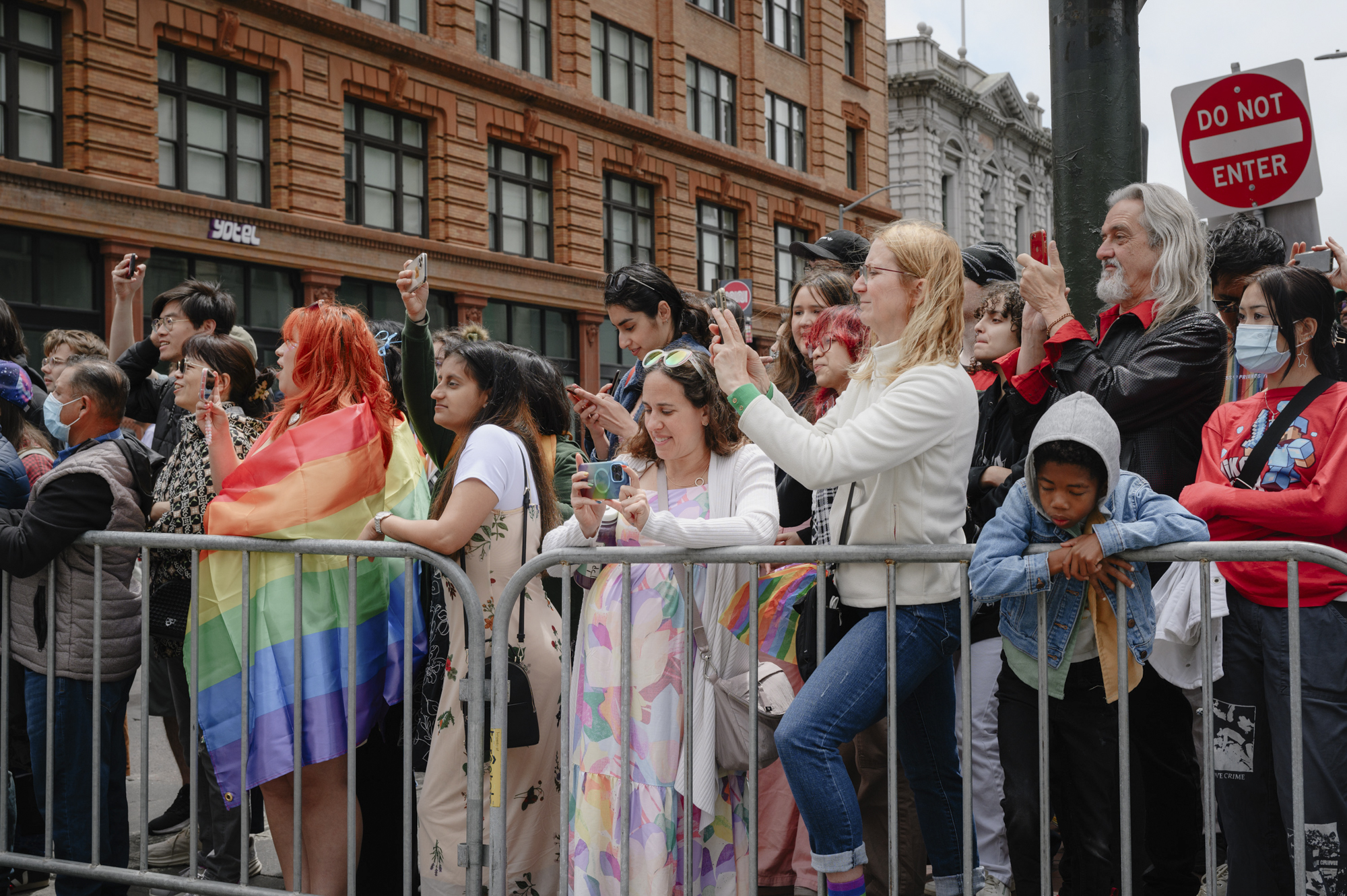 Onlookers wave and take photos as the Pride parade passes down Market Street in downtown San Francisco on June 25, 2023.