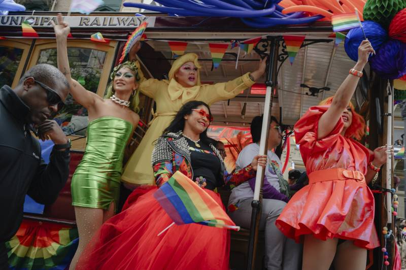 San Francisco Mayor London Breed, center, waves a Pride flag from the side of a cable car as the 2023 Pride parade passes down Market Street in downtown San Francisco on June 25, 2023.