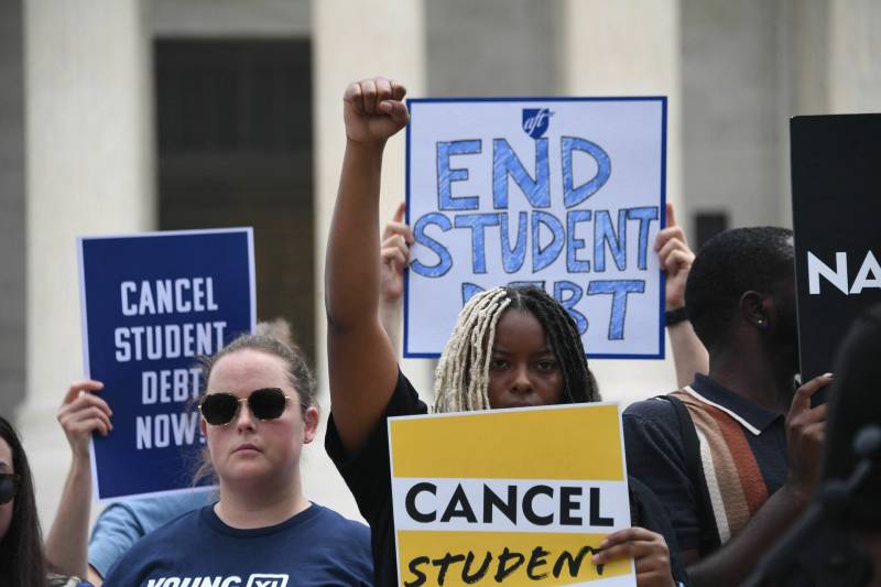 A group of protesters hold signs reading "Cancel Student Debt Now" and "End Student Debt"