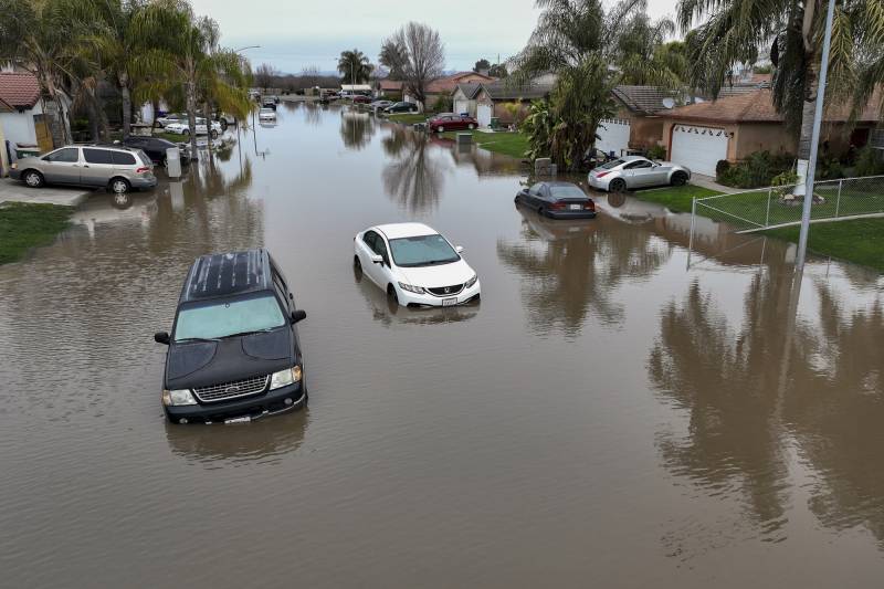 Cars sit in floodwaters in a residential neighborhood.