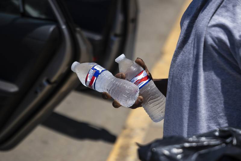 A hand holds two bottles of cold water.