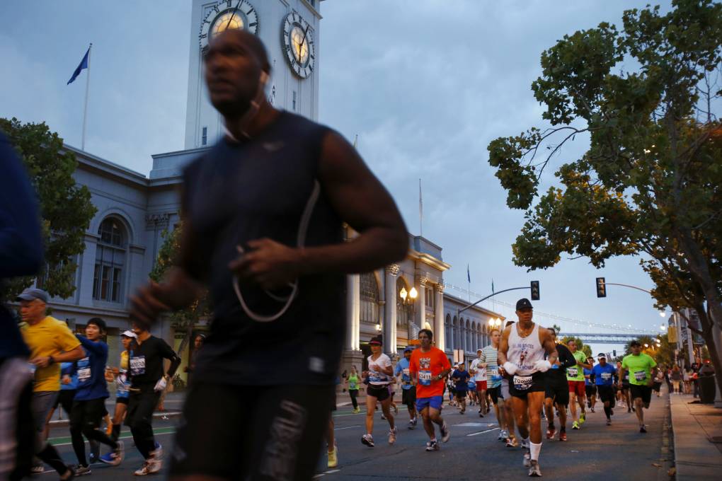 Dozens of people are seen running past the Ferry Building in San Francisco early in the morning.