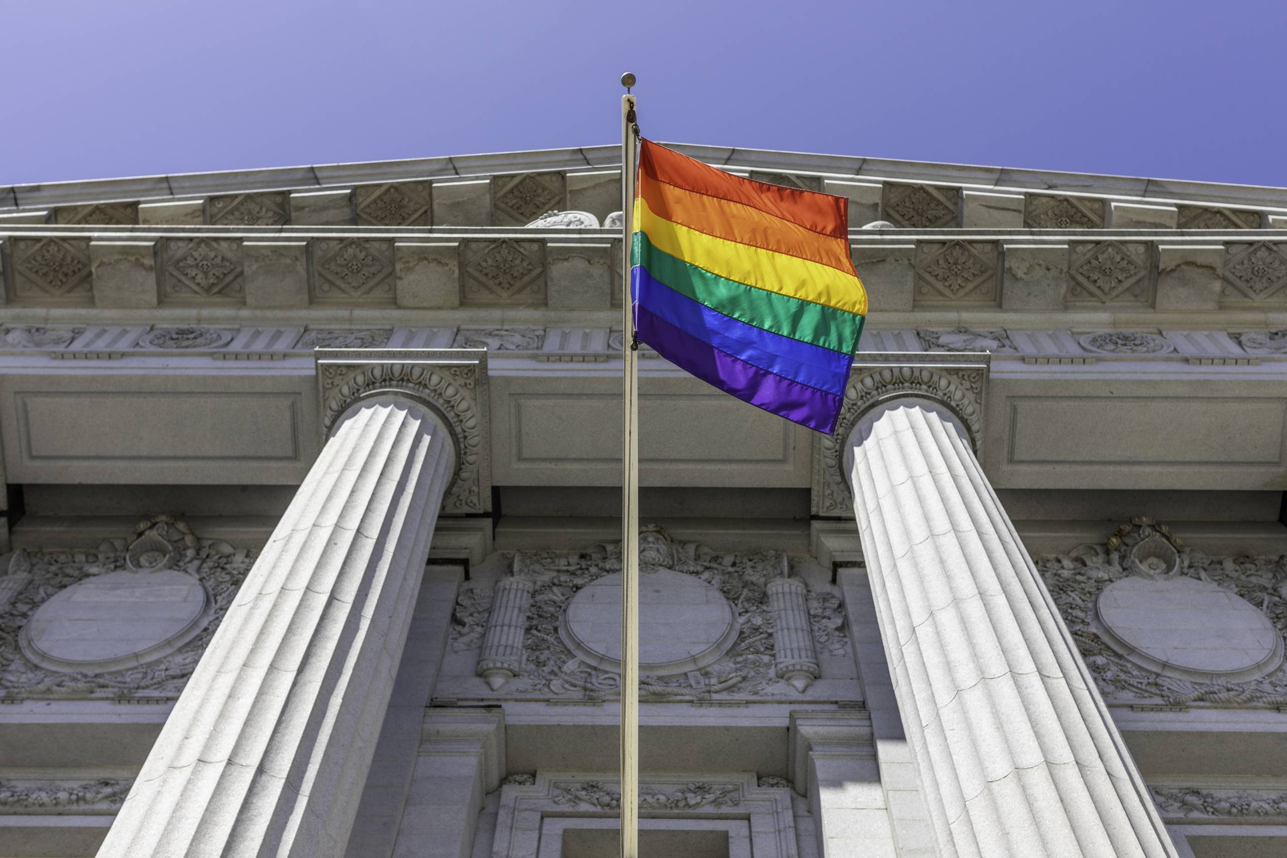 A rainbow flag hangs over a government building.