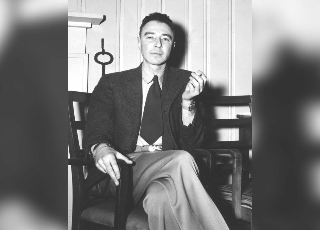 Black and white image of a man sitting in a chair smoking a cigarette.