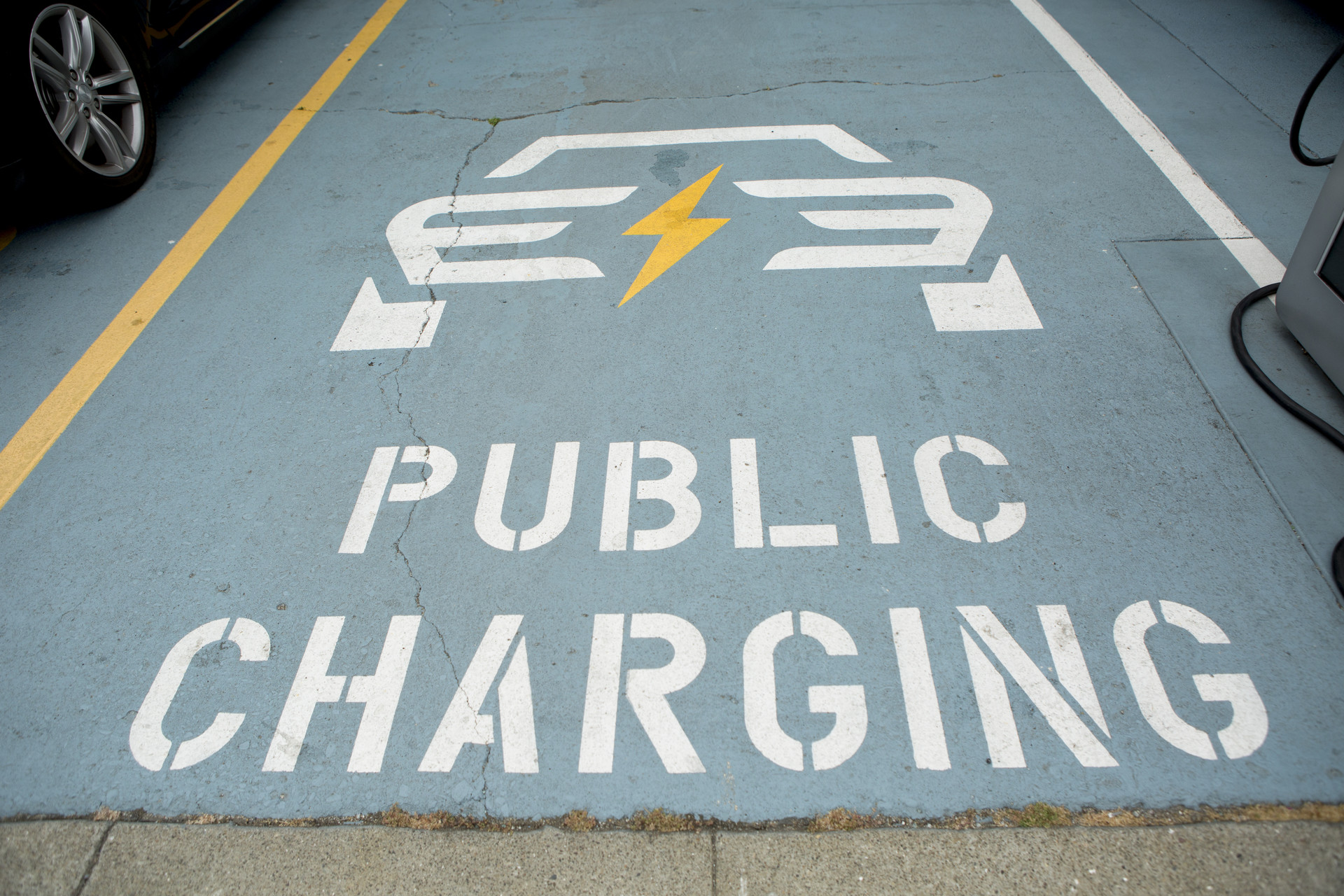A public parking space is marked with the words "public charging." An icon of a car with a lightning bolt is pictured above the parking space.