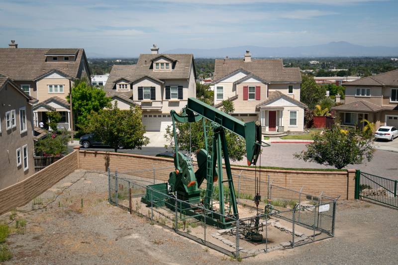 A pump jack extracts oil at a drilling site next to homes in Signal Hill on June 9, 2021.